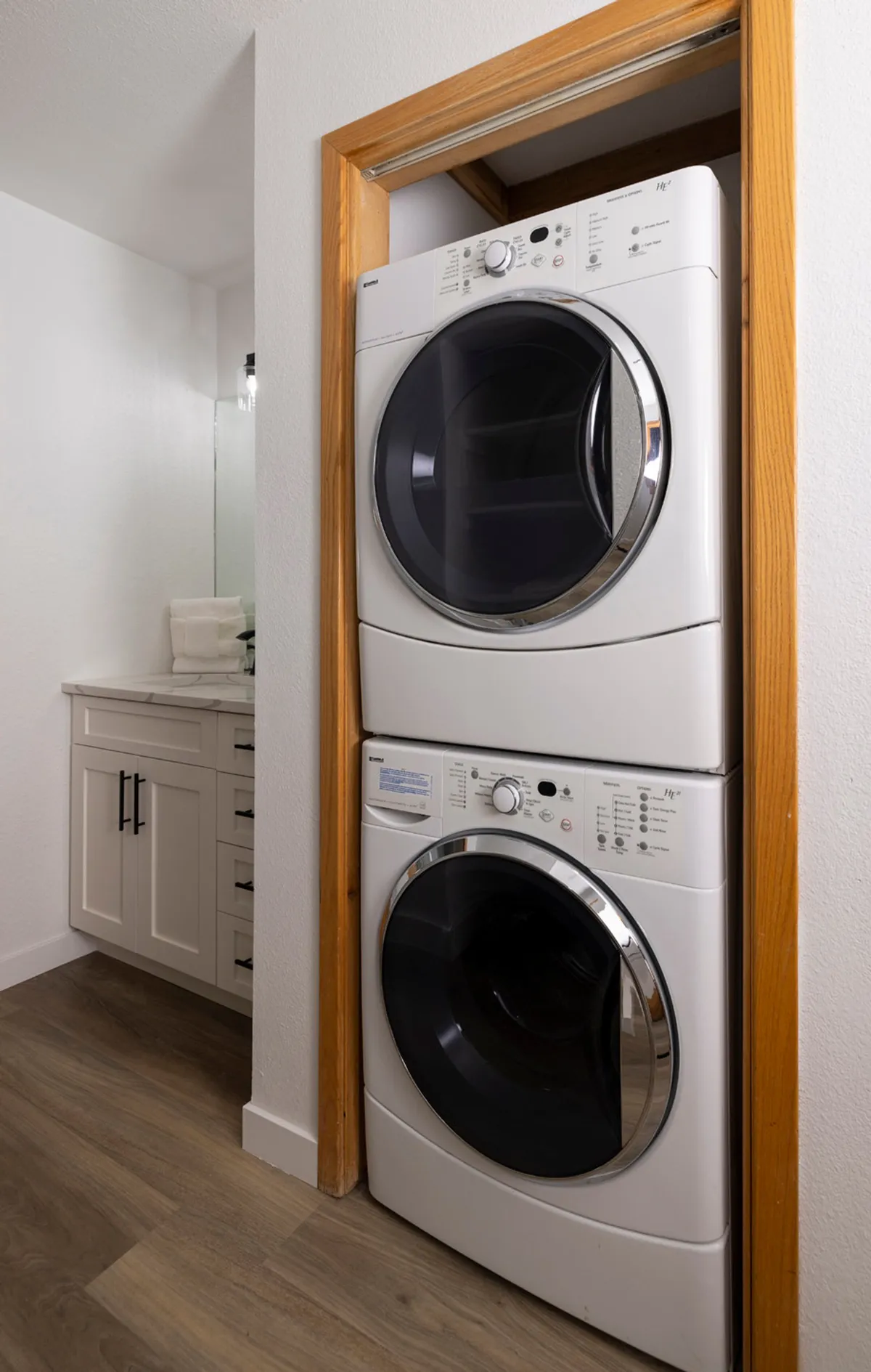 A compact laundry area with a stacked washer and dryer, modern vanity with sink, and sleek cabinetry. The setup is clean, efficient, and blends practicality with comfort—ideal for extended stays or families.