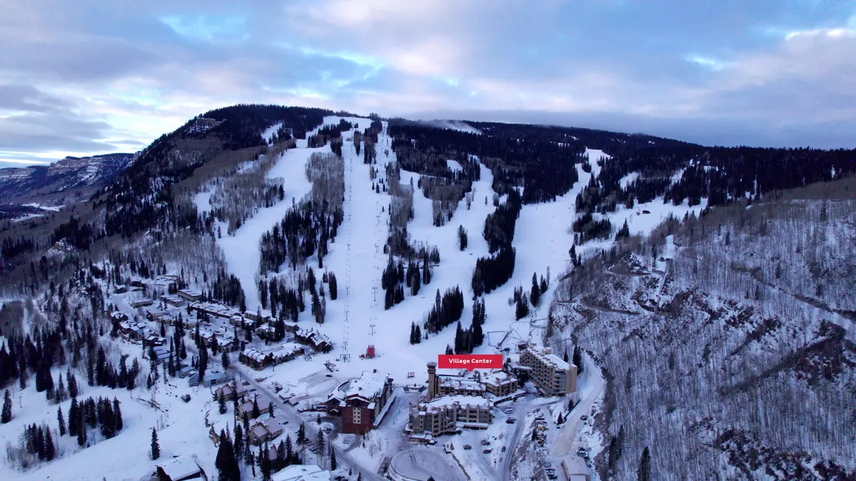This image captures the lively ski slopes of Purgatory Resort with skiers and snowboarders in action, the bustling village center, and a breathtaking backdrop of snow-covered mountains and trees. The scene is framed during an exciting sunrise, emphasizing both the thrill of morning runs and the vibrant resort community.